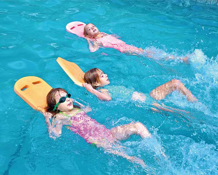 Children using swimming kickboard in pool